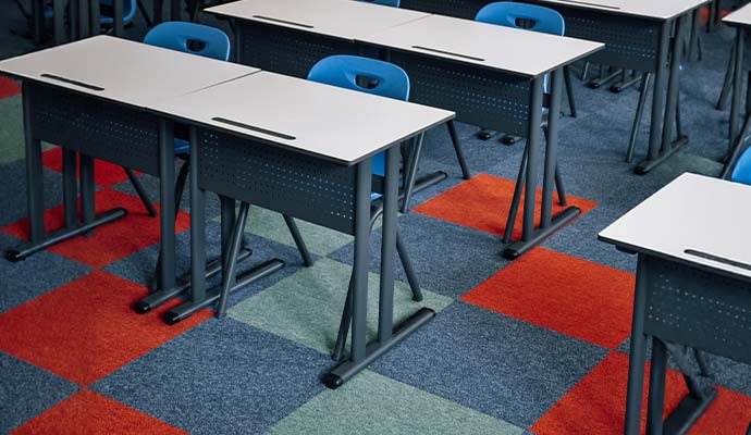 A school classroom featuring student desks and colorful patterned carpet floor