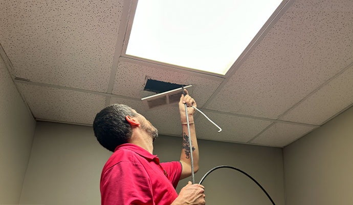 Technician servicing a ceiling vent for UV air purification installation