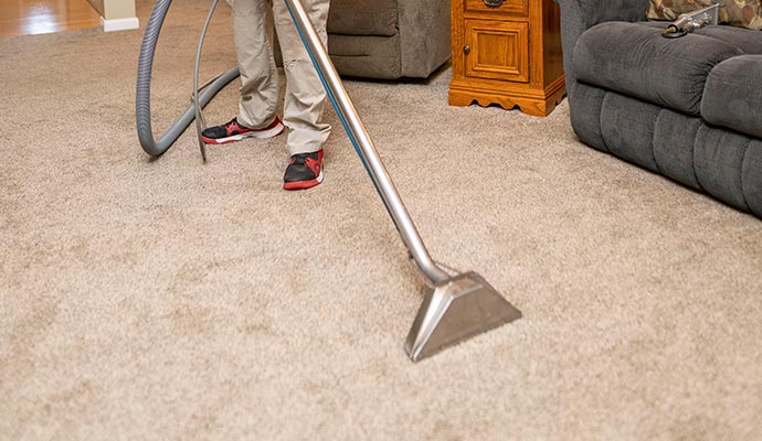 person cleaning beige carpet with vacuum cleaner