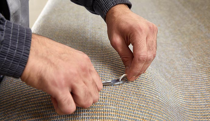 Professional expert using a small hand tool to repair and restore a carpet