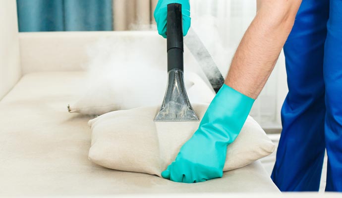 Person cleaning upholstery using equipment