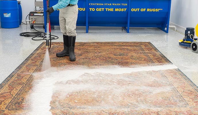 A worker pressure-washes a carpet