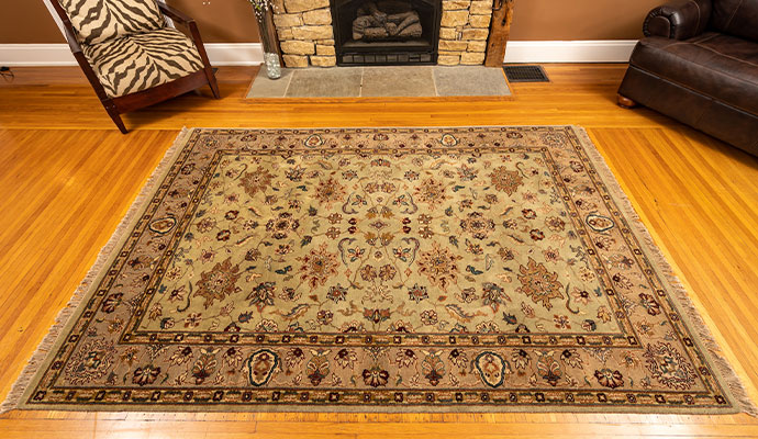 A clean carpet placed on a wooden floor in front of a stone fireplace