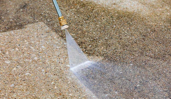 Pressure washer nozzle spraying high-pressure water to deep clean concrete pavement