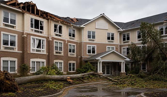 Assisted living facility building damaged by severe storm with fallen tree and broken roof