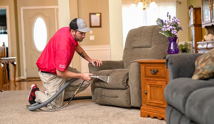A work-man is cleaning Couches and sofa.
