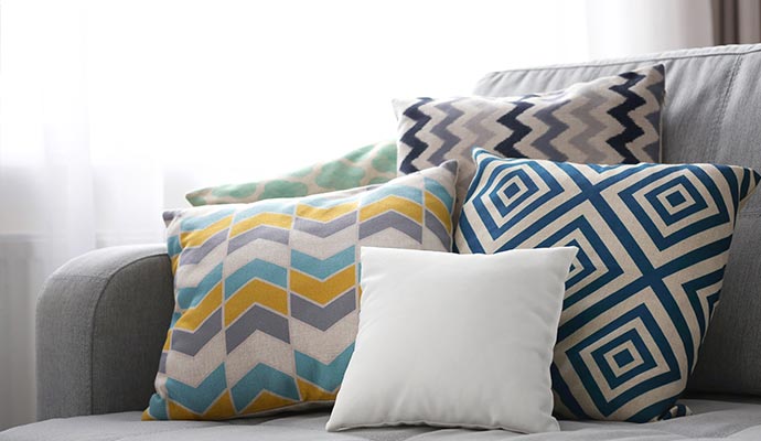 A collection of clean, patterned decorative pillows arranged neatly on a grey fabric sofa