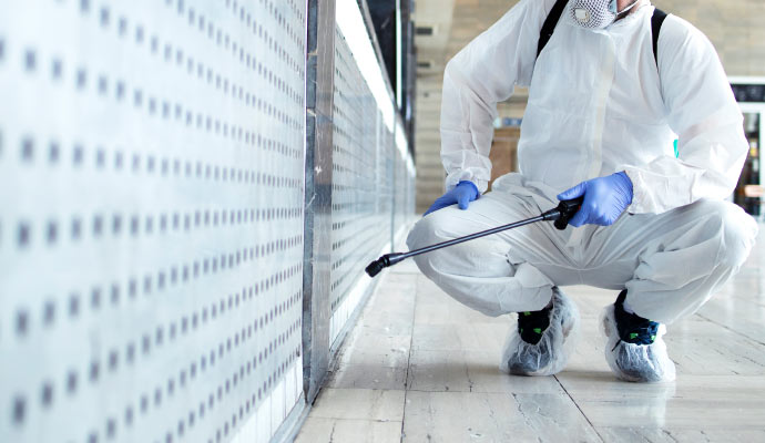 Person wearing protective gear disinfecting surface