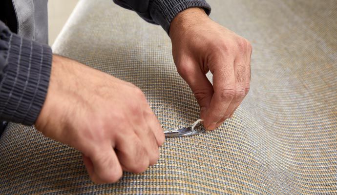 Professional expert using a small hand tool to repair and restore a carpet