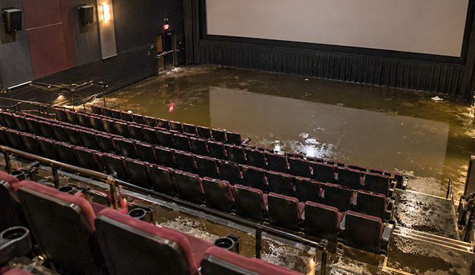 Flooded movie theater auditorium with standing water near the screen