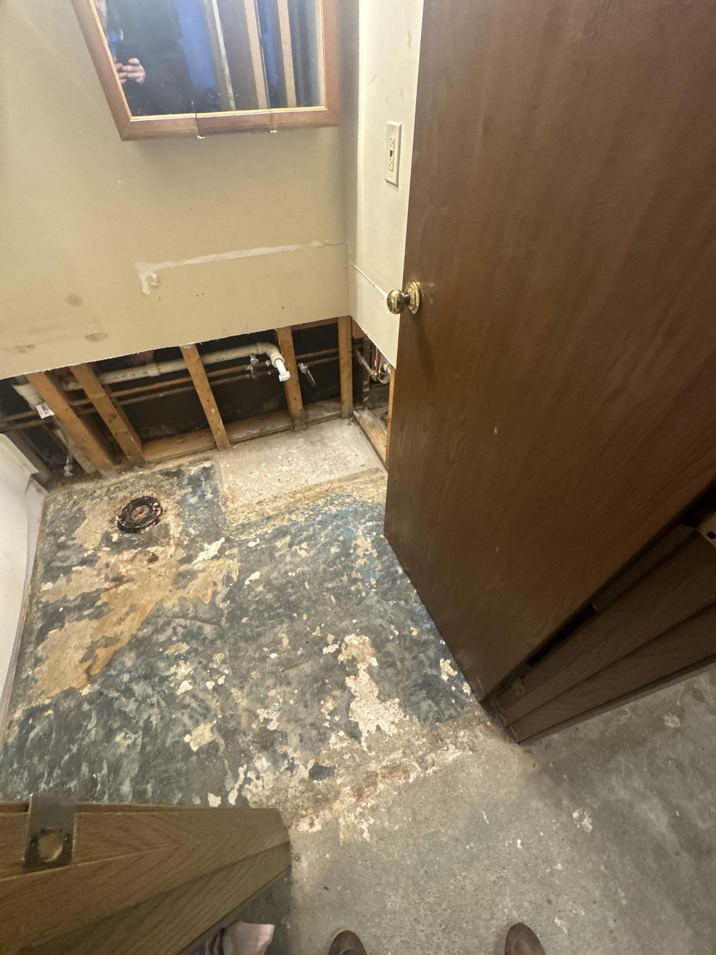 Extensive water damage to bathroom subfloor after tile removal, demonstrating the need for Teasdale Fenton's restoration.