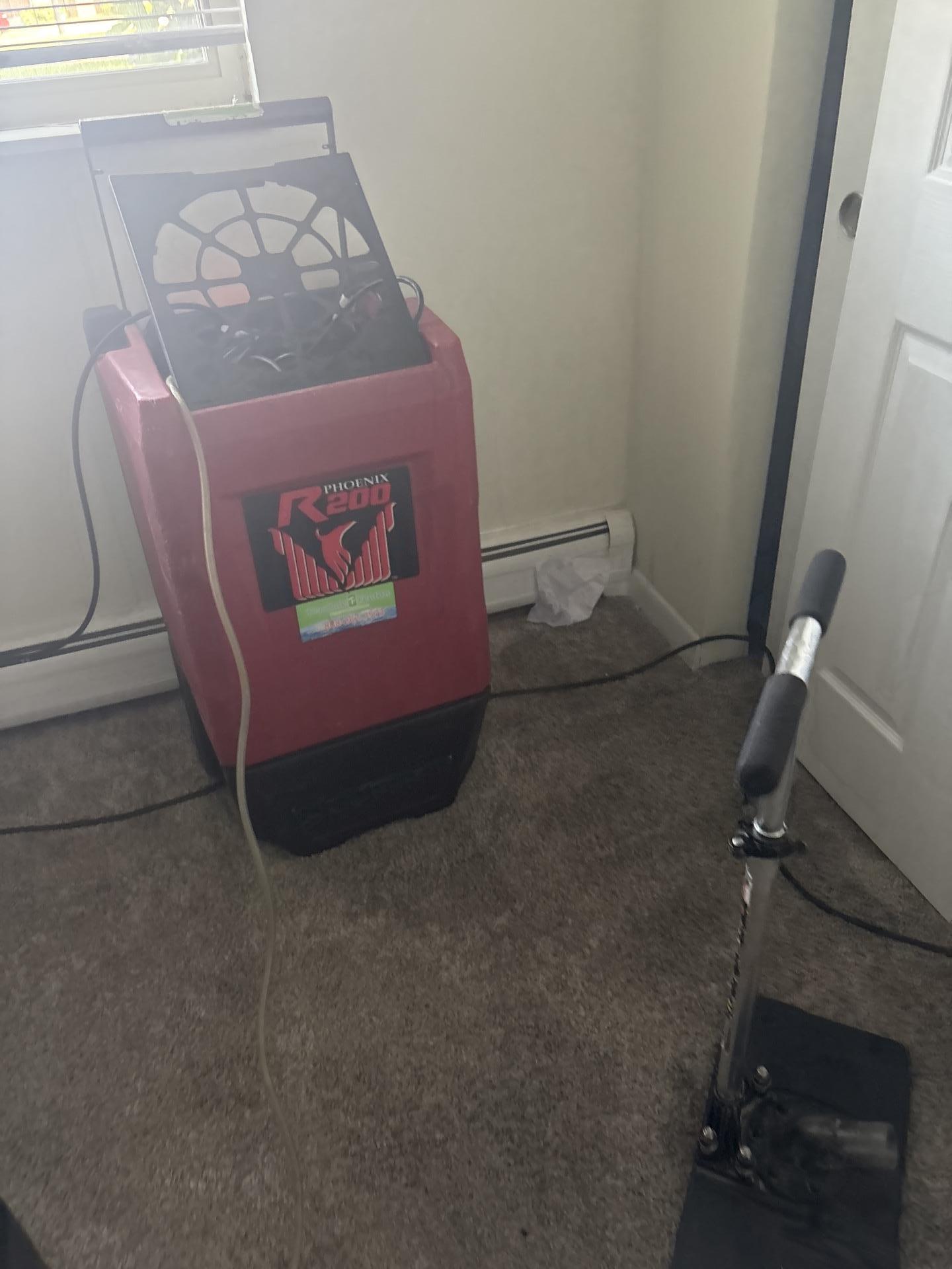 Commercial dehumidifier and extraction equipment set up for professional carpet water damage restoration.