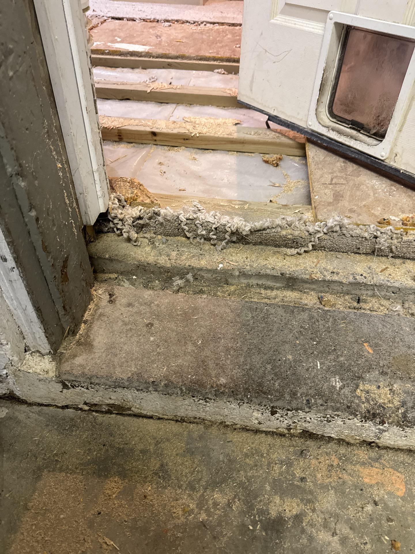 Saturated carpet removed to expose structural wood floor joists during emergency residential water mitigation.