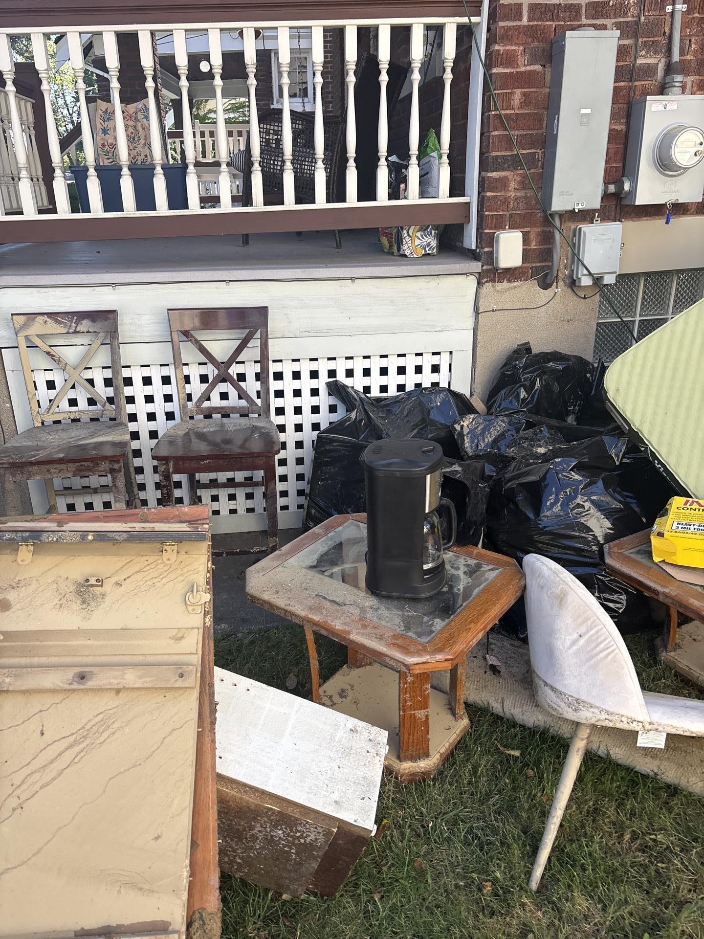 Flood-damaged furniture and debris relocated outside during emergency residential pack-out and mitigation services.