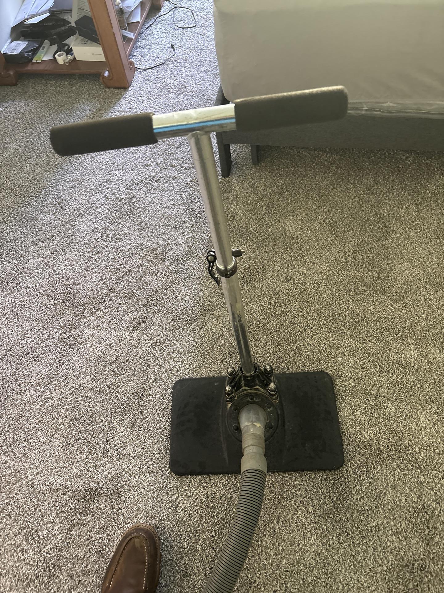 Close-up of a professional carpet cleaning wand extracting water from a grey residential carpet after water damage.