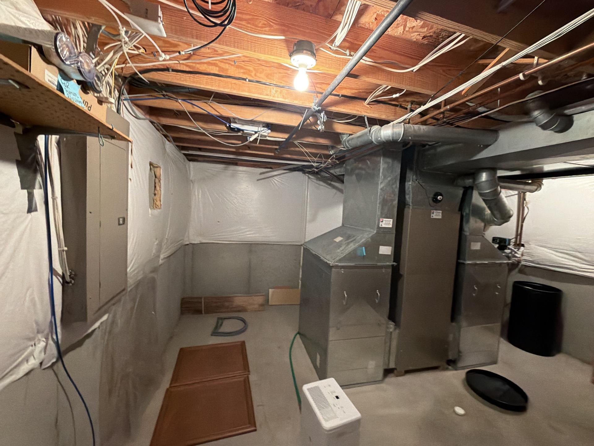 Mold mitigation equipment, including a large dehumidifier, set up in a basement with an HVAC system and exposed ceiling joists to control moisture and clean air.