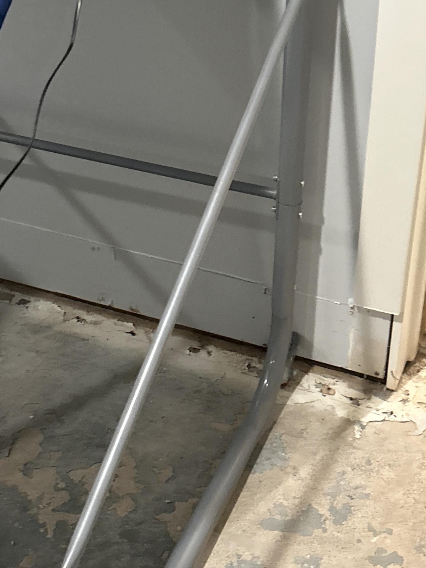 Close-up of water-damaged wall baseboard and concrete subfloor prior to structural drying setup