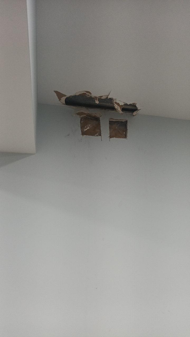 Close-up of cut plasterboard around an air vent opening inspected for condensation and moisture levels