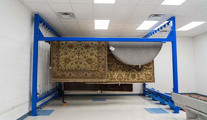 Large ornate rugs hanging on a blue metal drying rack