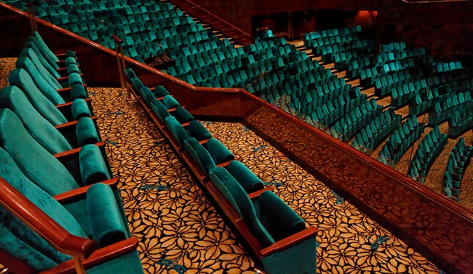 Large theater auditorium with teal seating and patterned carpeting