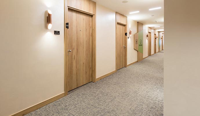 A clean, modern hotel hallway with carpeted floors.