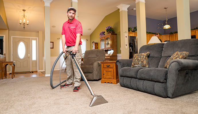 Professional technician performing carpet cleaning service inside living room