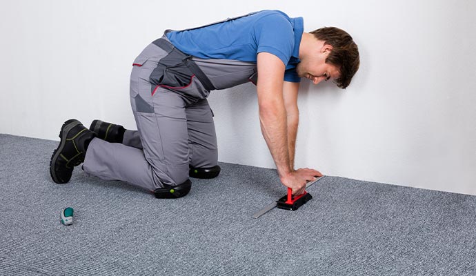 Professional carpet installer trimming carpet edges in a residential room