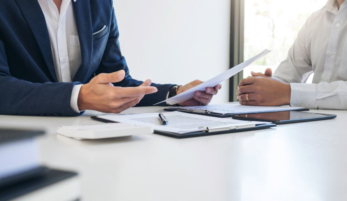 A professional explaining paperwork to a client at a desk