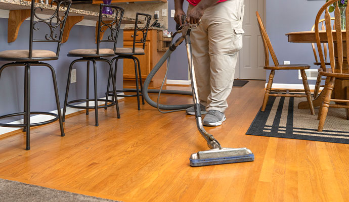 A person cleaning a hardwood floor using a vacuum cleaner