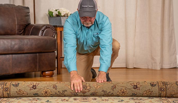 Teasdale employee rolling up a rug for pickup service Teasdale employee rolling up a rug for pickup service