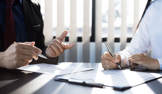Two people reviewing and signing documents at a desk