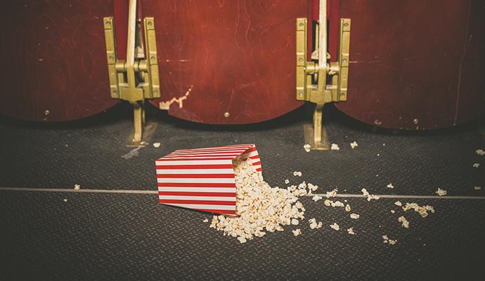 Spilled popcorn bucket on cinema floor carpet