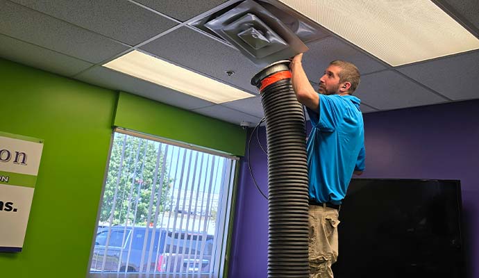 Professional technician cleaning ceiling air duct vent