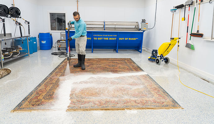 Technician cleaning oriental area rug with water hose