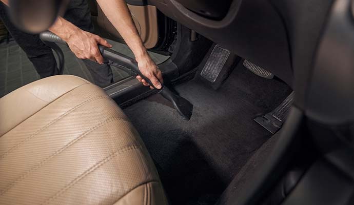 Professional technician vacuuming vehicle interior carpet