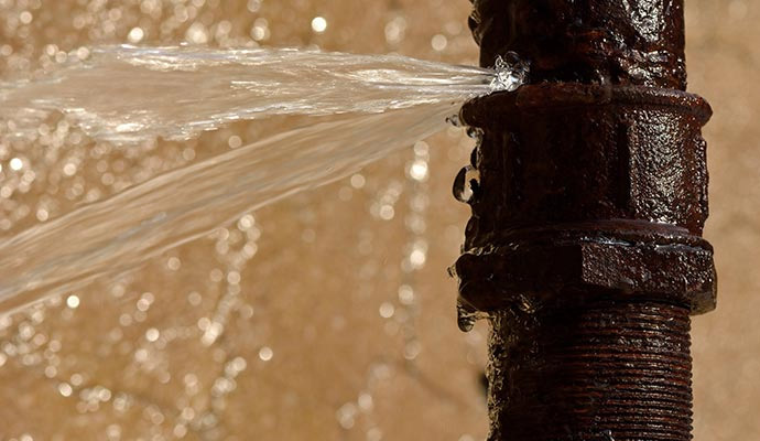 A burst rusty iron pipe leaking water