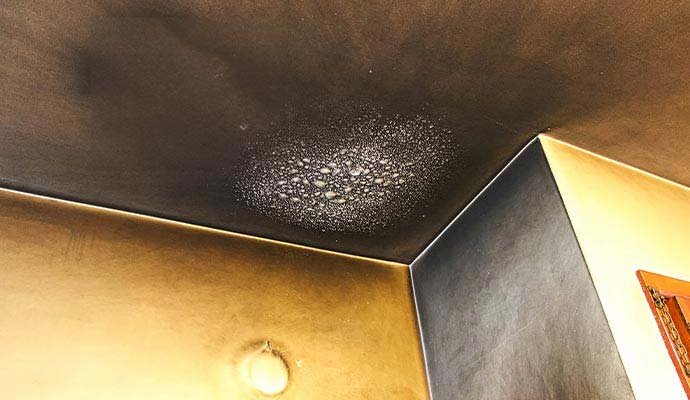 Heavy soot buildup and heat blistered paint on a ceiling from fire damage.