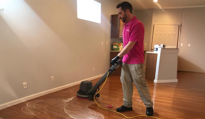 A professional person is cleaning wood floor with industrial cleaner
